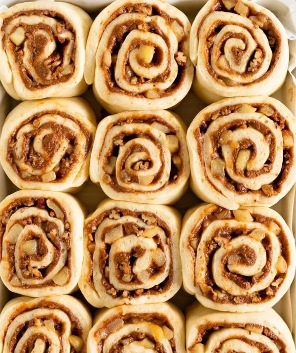Delicious apple pecan cinnamon rolls topped with icing on a plate.