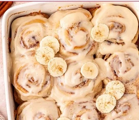Delicious banana bread cinnamon rolls with frosting on a plate.