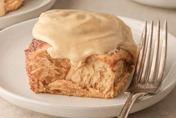 Freshly baked gingerbread cinnamon rolls drizzled with icing on a festive plate.