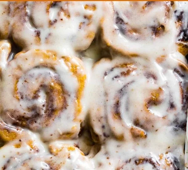 Gluten-free pumpkin cinnamon rolls topped with cream cheese frosting.