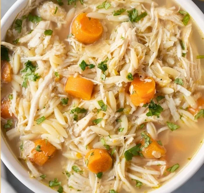 Bowl of Greek Lemon Chicken Soup with lemon slices and herbs.