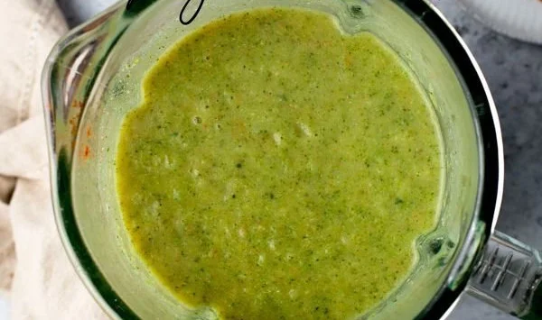Healthy broccoli soup served in a bowl with fresh ingredients on the side
