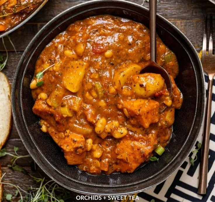 Bowl of hearty vegan sweet potato stew garnished with herbs and spices.