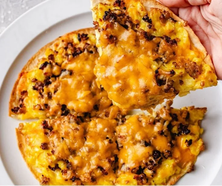 Delicious high protein sausage and egg breakfast pizza on a wooden table