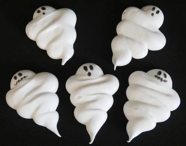 Spooky meringue ghosts for Halloween dessert decoration.