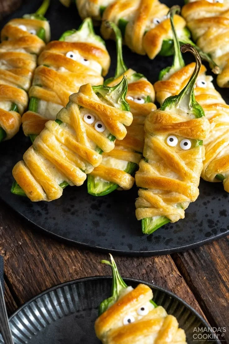 Mummy wrapped jalapeño poppers stuffed with cream cheese for a festive appetizer