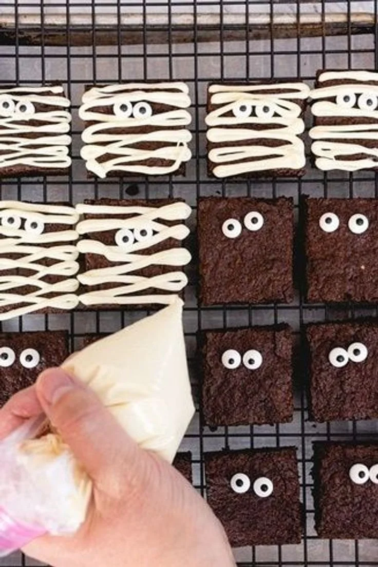 Spooky mummy brownies decorated with white icing and candy eyes for Halloween treats